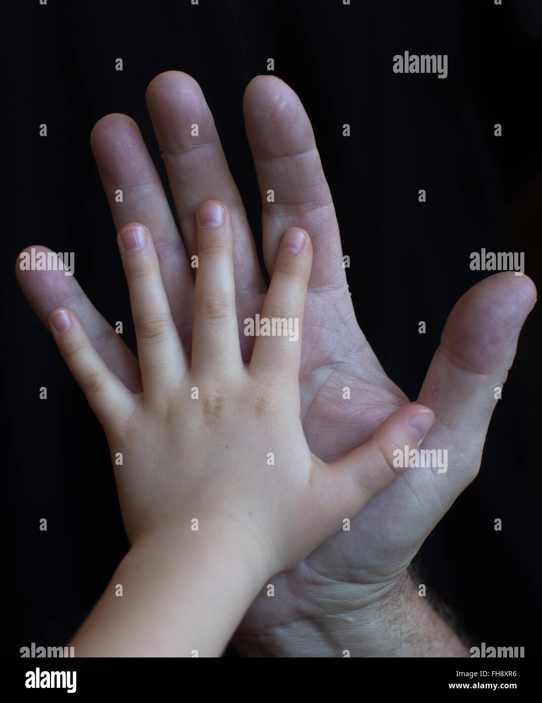 A grandfather and his granddaughter compare hands Stock Photo