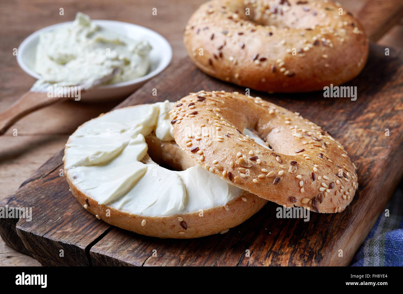 Bagel with cream cheese on wooden table Stock Photo