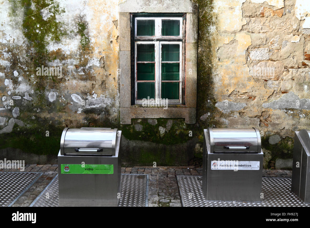 New metal recycling bins for glass and domestic waste outside old stone house, Caminha, northern Portugal Stock Photo