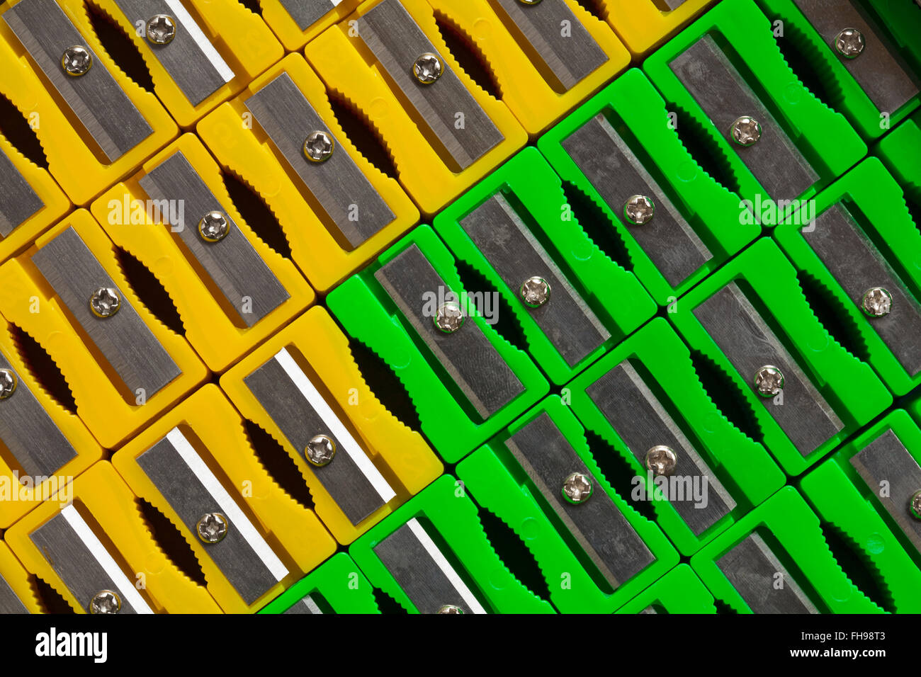 Rows of green and yellow plastic pencil sharpeners placed diagonally Stock Photo