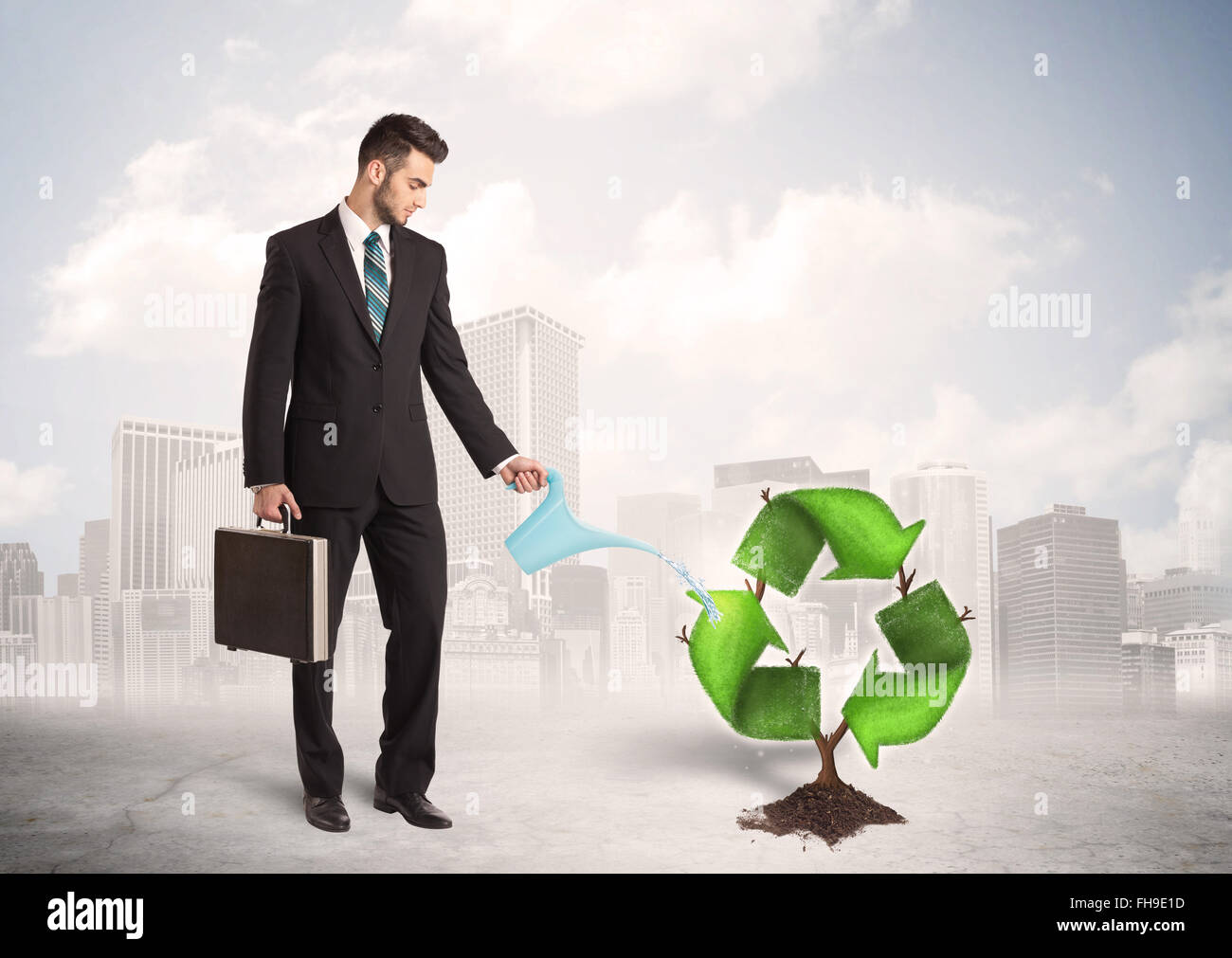 Business man watering green recycle sign tree on city background Stock Photo