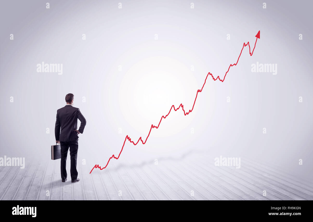 Standing businessman with red graph arrow Stock Photo - Alamy