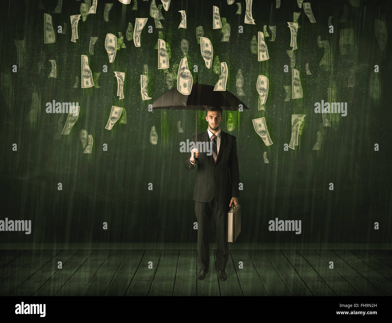 Businessman standing with umbrella in dollar bill rain concept Stock Photo