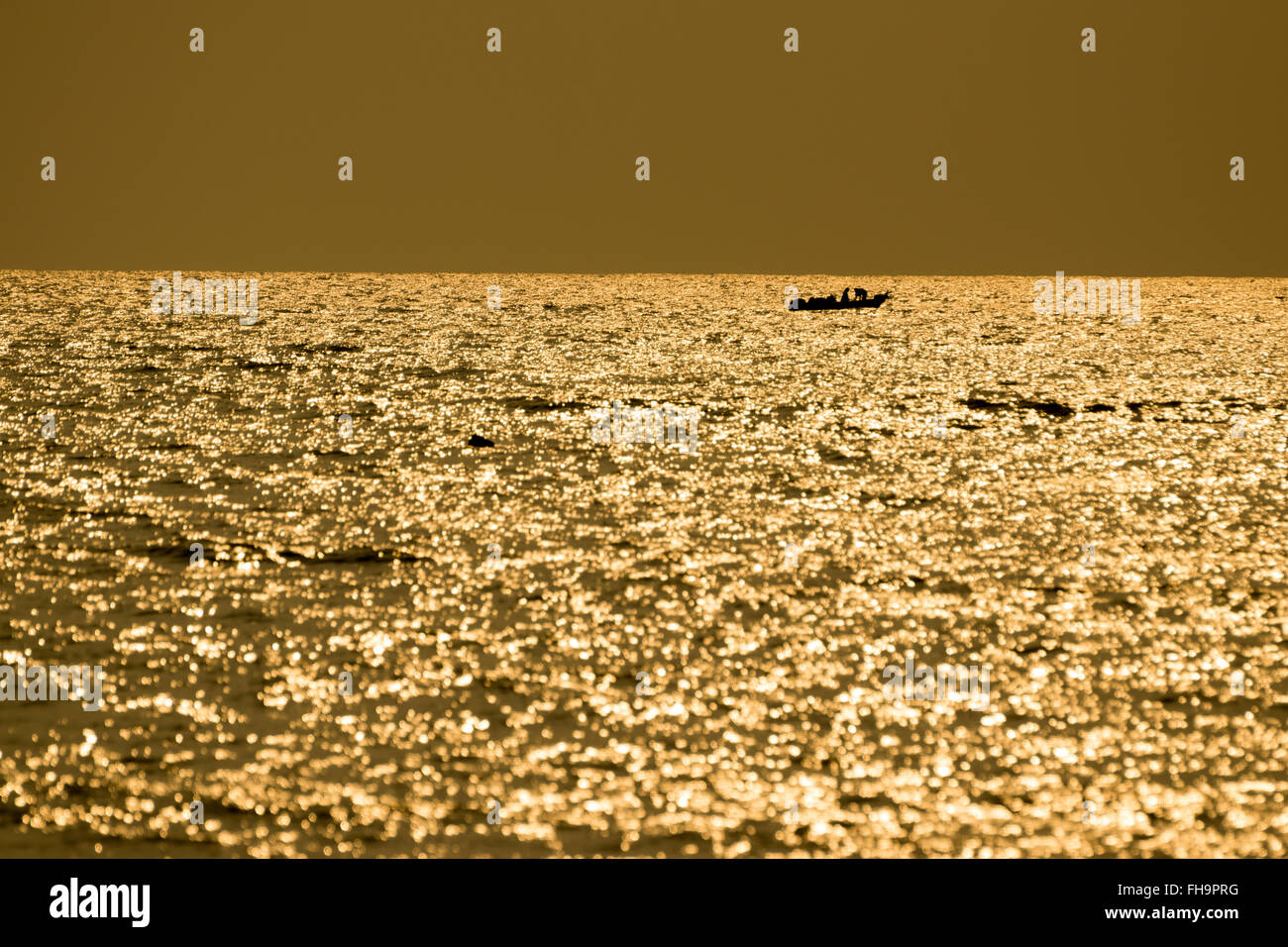 Fishing boats floating in the sea with the golden light of the morning sun. Stock Photo