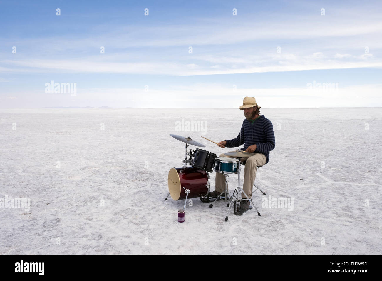 A musician plays the drums in the landscape of the Uyuni Salt Flats Stock Photo