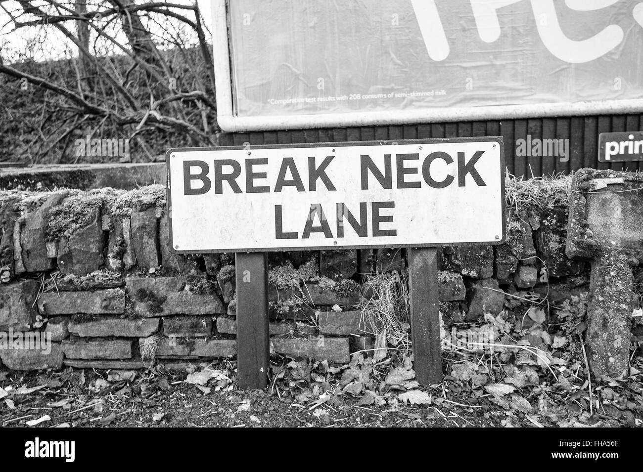 Break Neck Lane road sign in front of low stone wall Stock Photo