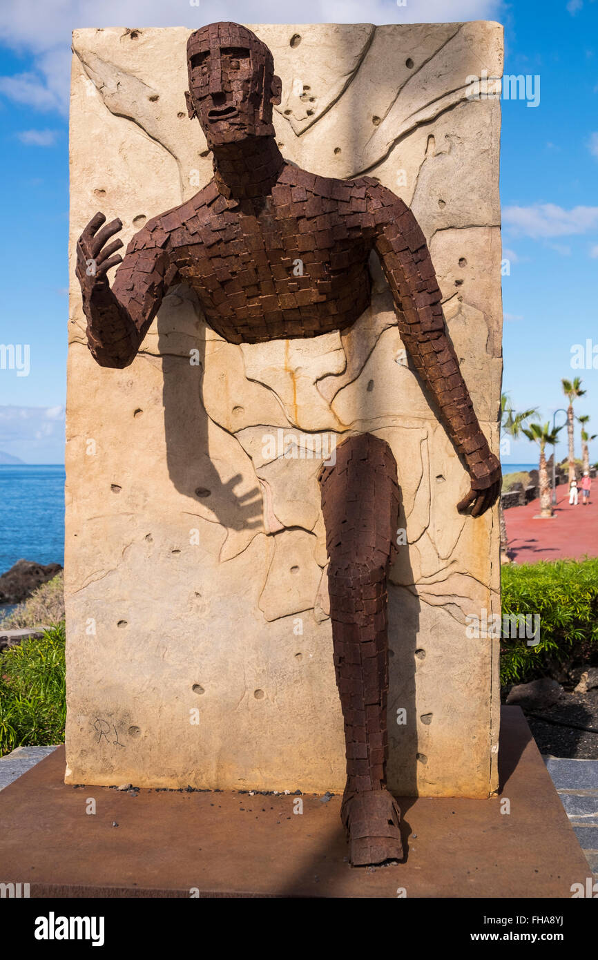 Sculpture of a running man breaking through a wall. Allegory for sports person pushing their boundaries. Playa San Juan, Tenerif Stock Photo