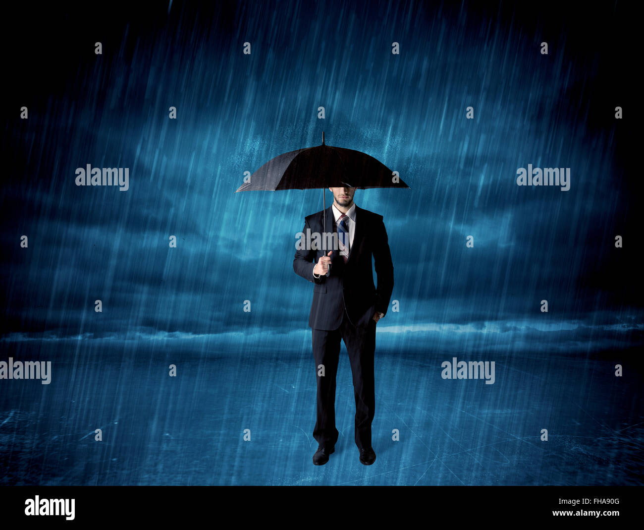 Business man standing in rain with an umbrella Stock Photo
