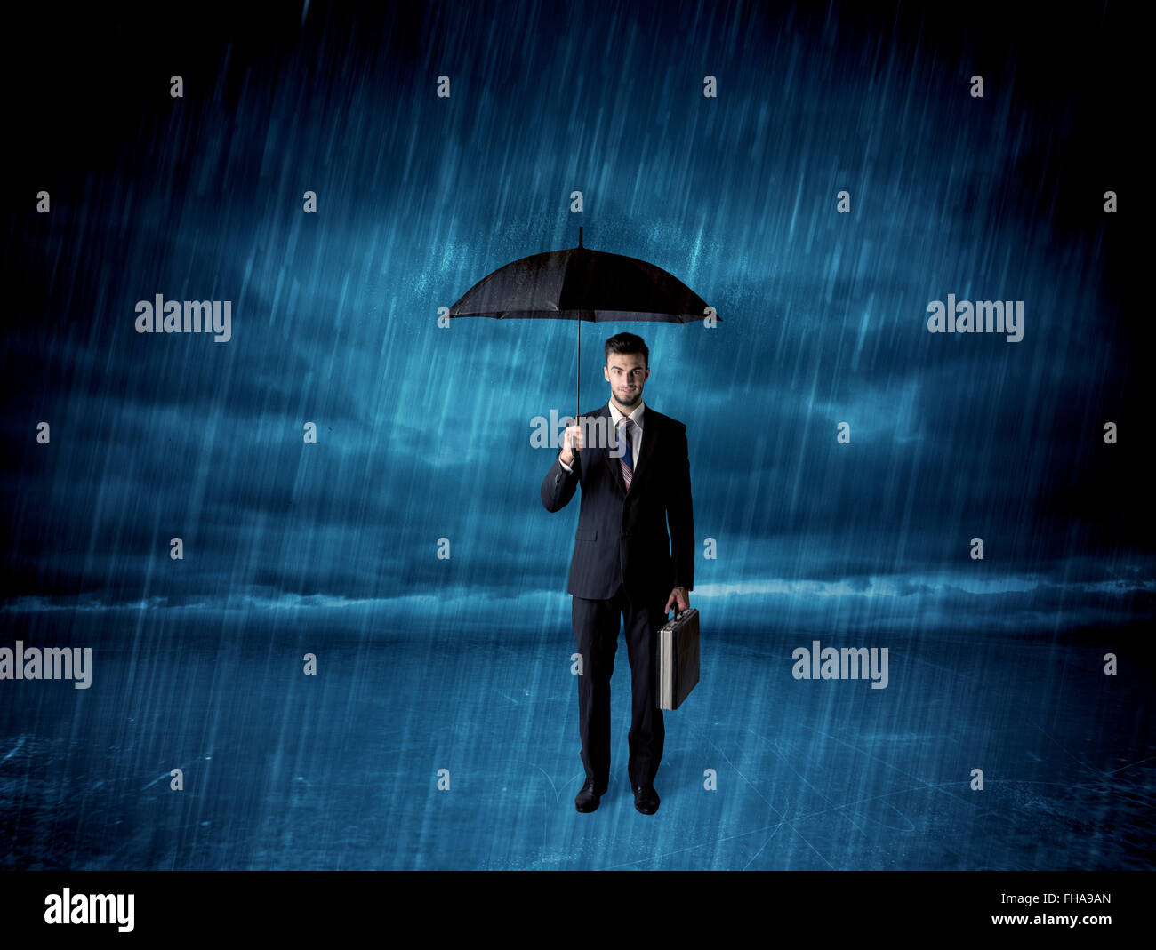 Business man standing in rain with an umbrella Stock Photo