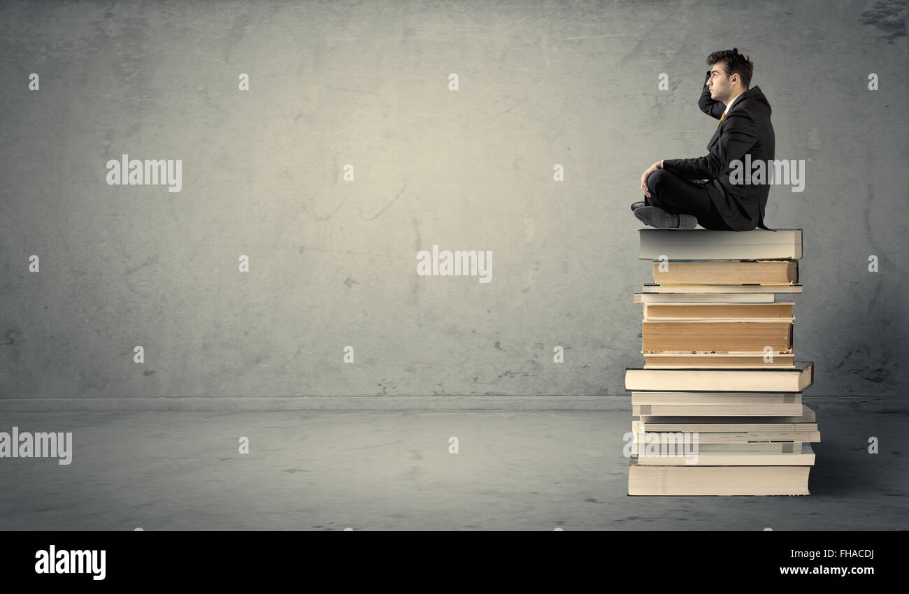 Student sitting on stack of books Stock Photo - Alamy