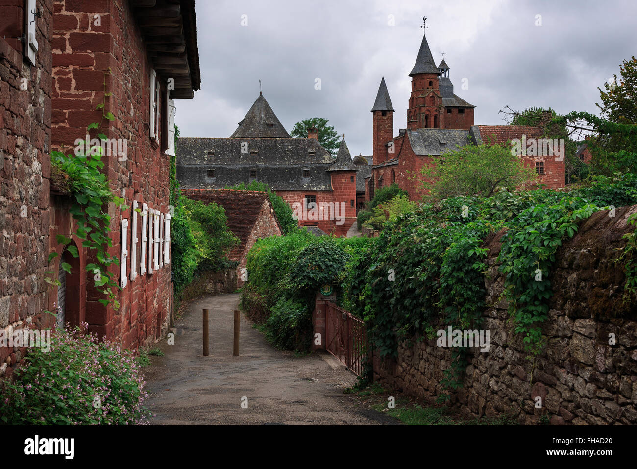 View on a path towards the tower of the church in red stone in the red village Collonges-la-Rouge in Dordogne area, France. Stock Photo