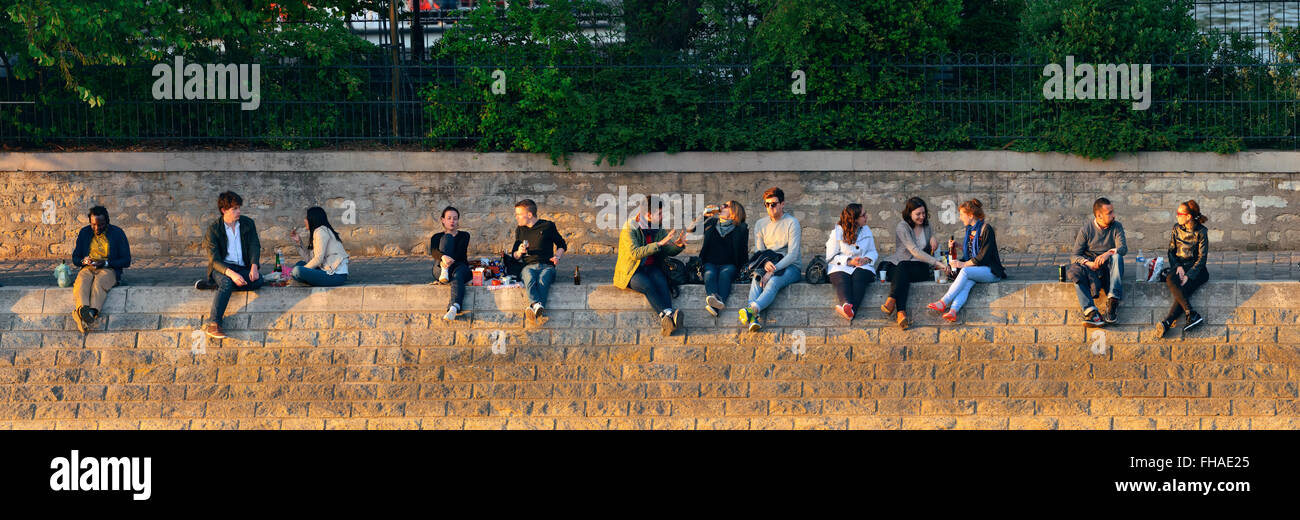 PARIS, FRANCE - MAY 13: People enjoy sunset light by River Seine on May 13, 2015 in Paris. With the population of 2M, Paris is the capital and most-populous city of France Stock Photo