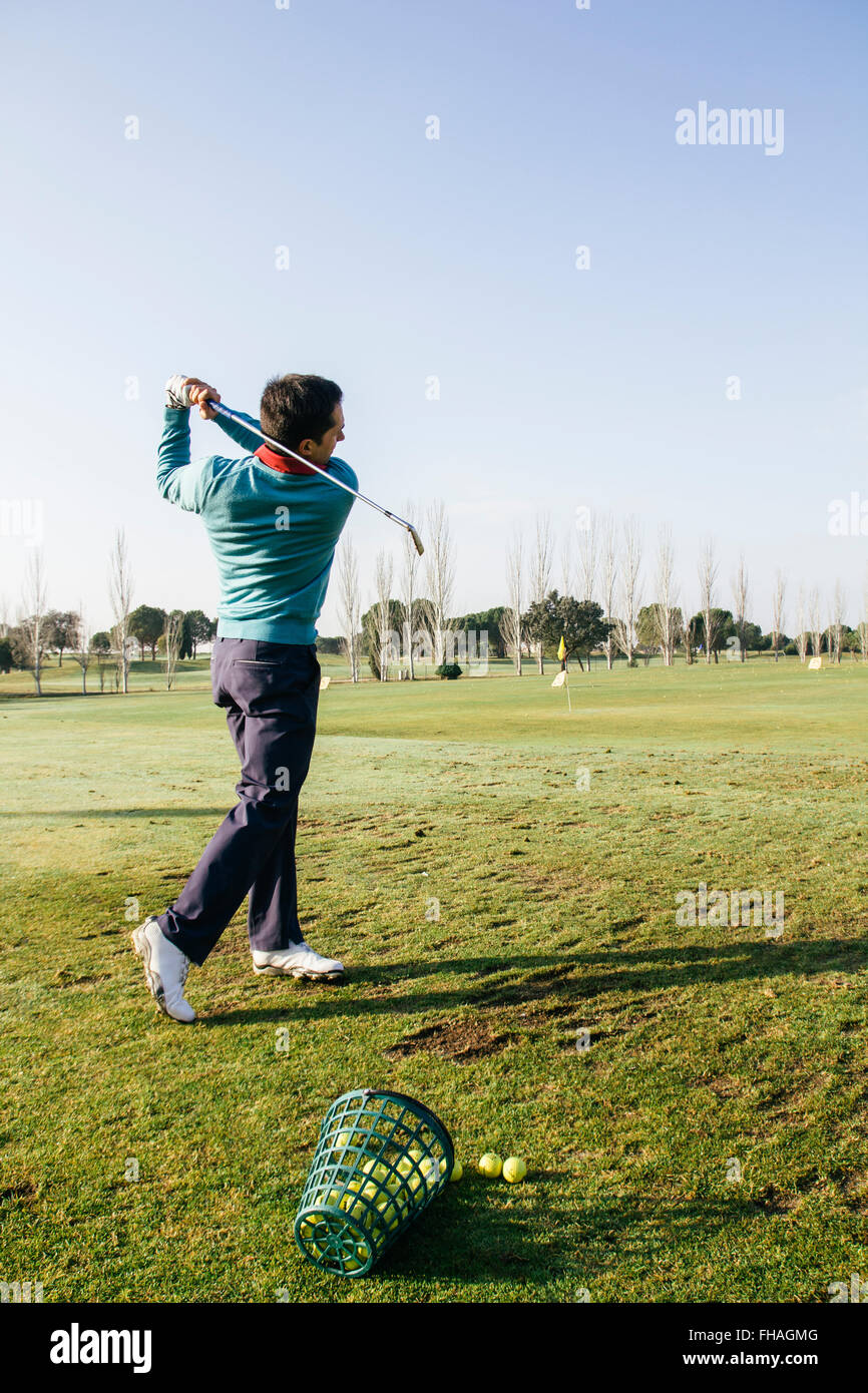 Golfer hitting a golf ball in the driving range of a golf club Stock