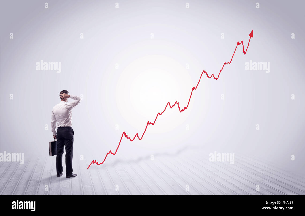Standing businessman with red graph arrow Stock Photo - Alamy