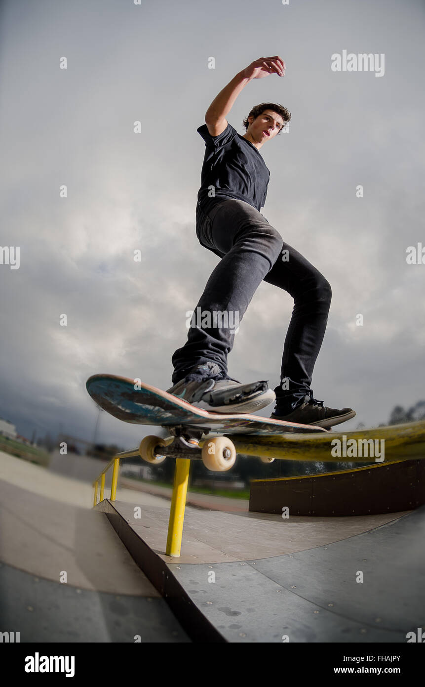 Skateboarder doing a board slide over the rail at the skate park Stock