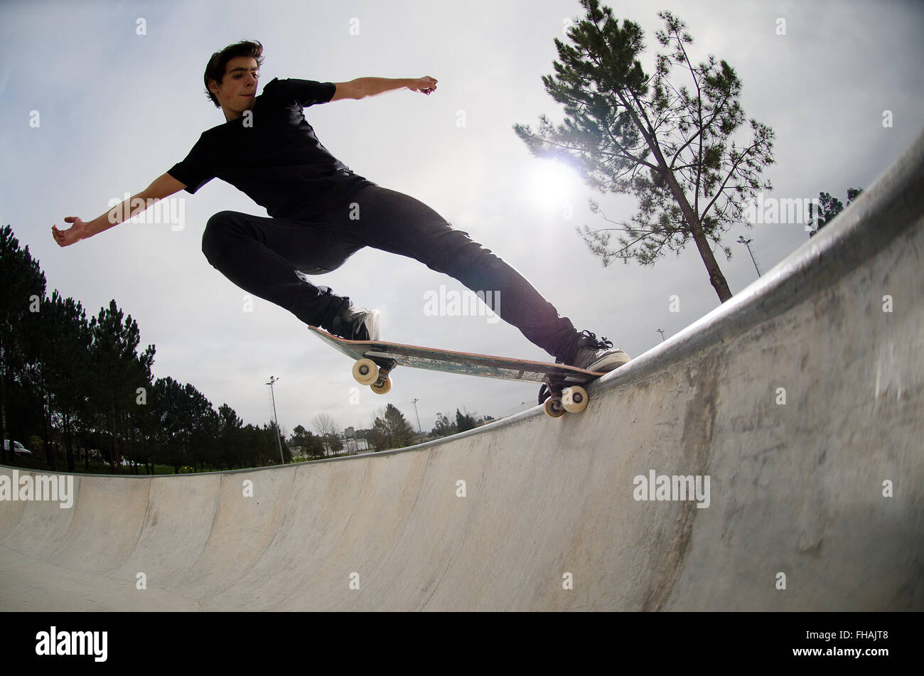 Skateboarder doing a tail slide on a croncrete pool at the skate park
