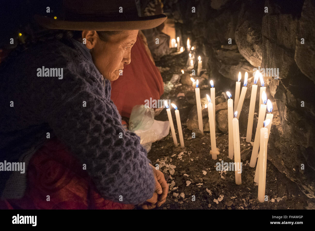A woman puts candles in the sanctuary in the celebration of the feast of Qoyllur Riti Stock Photo