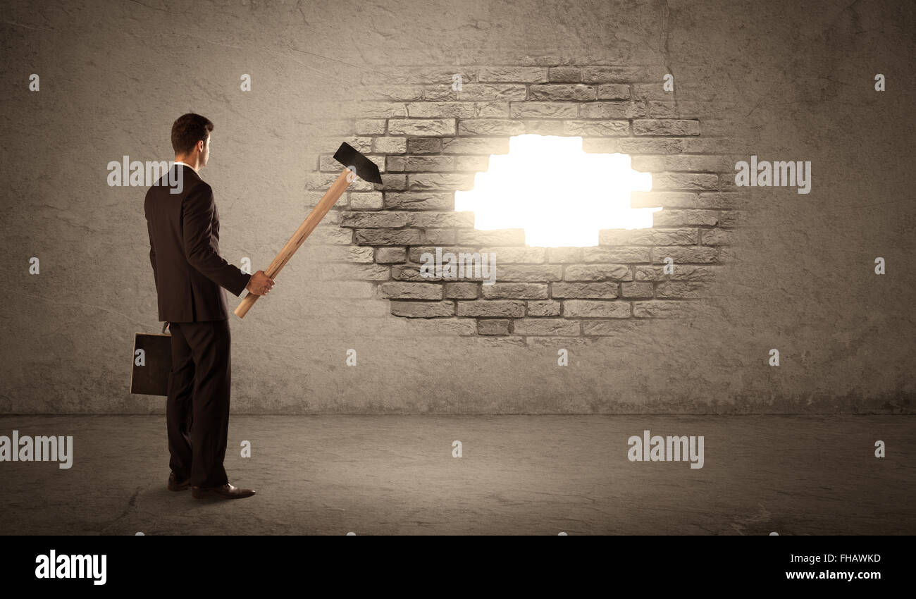 Business man hitting brick wall with hammer and opening a hole Stock