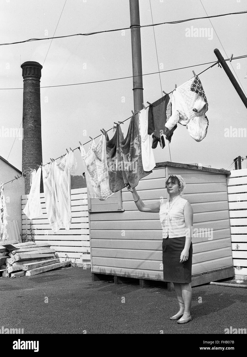 Woman hanging out her washing during the 1960s near factory chimneys Jackfield Uk Stock Photo