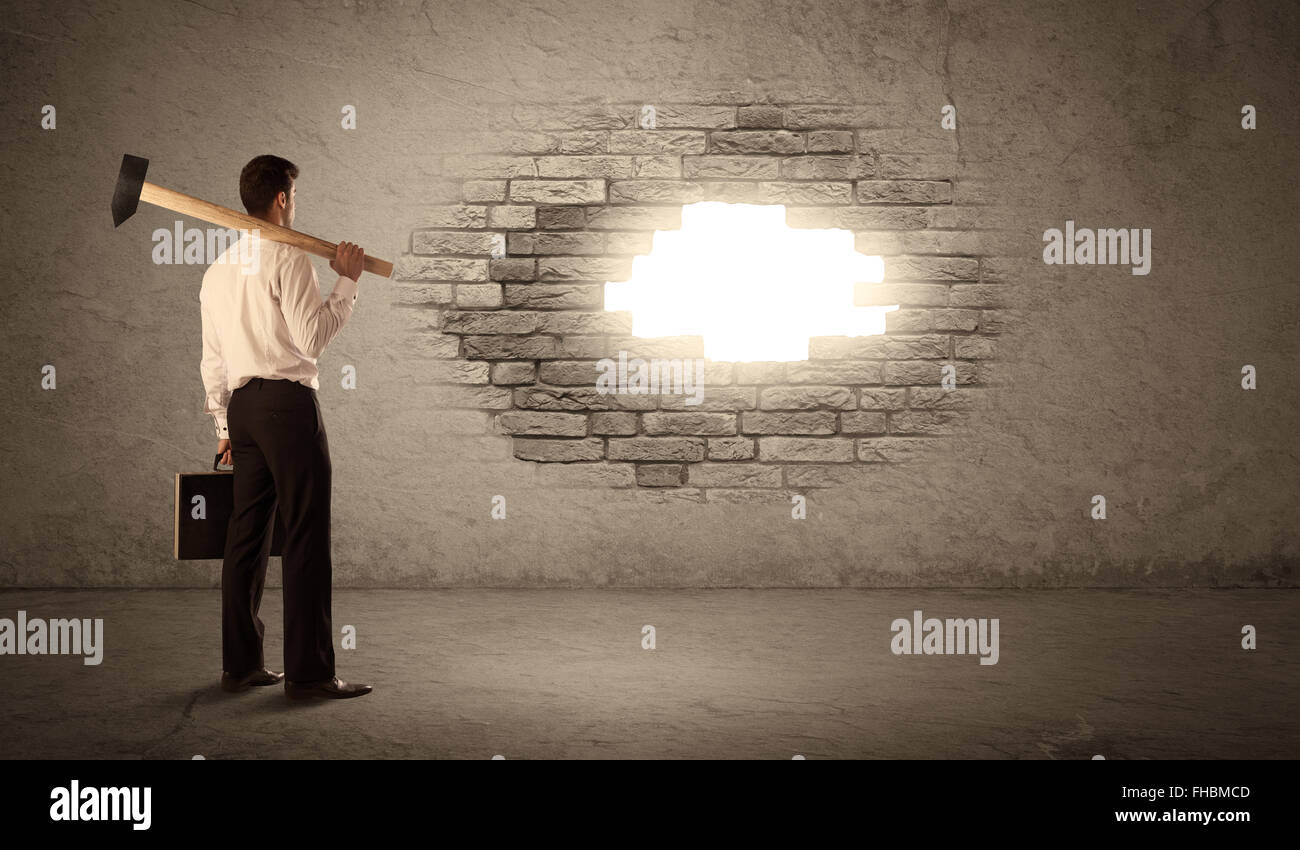 Business man hitting brick wall with hammer and opening a hole Stock Photo Alamy