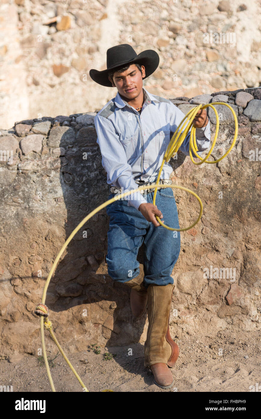 A Mexican charro or cowboy poses in cowboy hat and lasso
