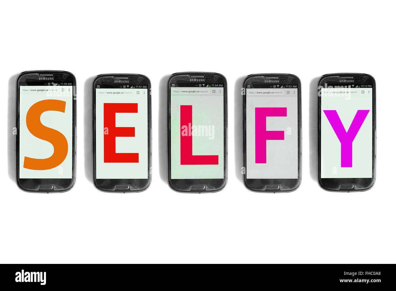 Selfy written on the screens of smartphones photographed against a white background. Stock Photo