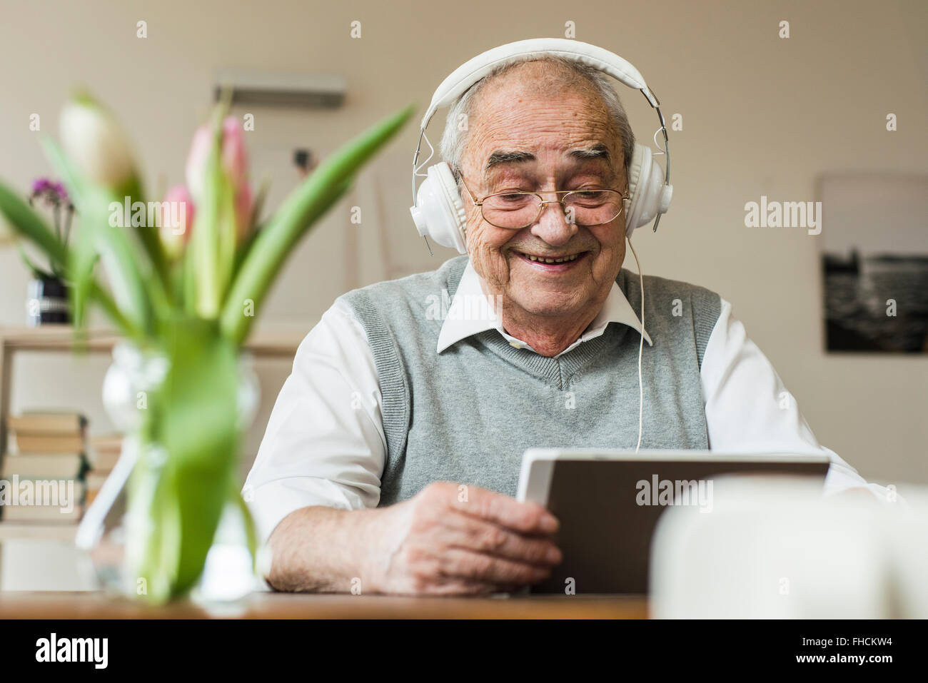 Senior man using mini tablet and headphones for skyping at home Stock Photo