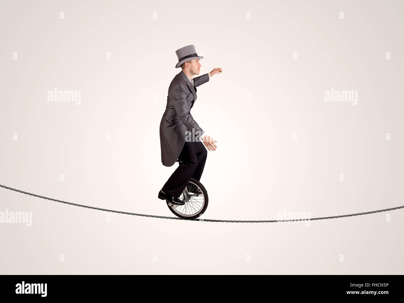 Extreme business man riding unicycle on a rope Stock Photo - Alamy