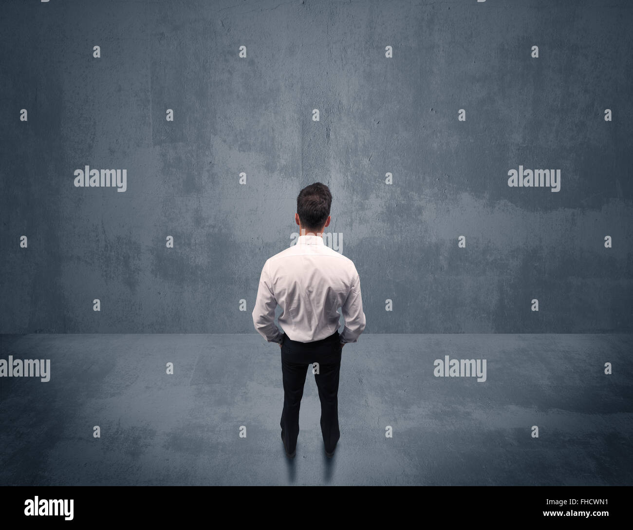 Businessman standing in front of urban wall Stock Photo - Alamy