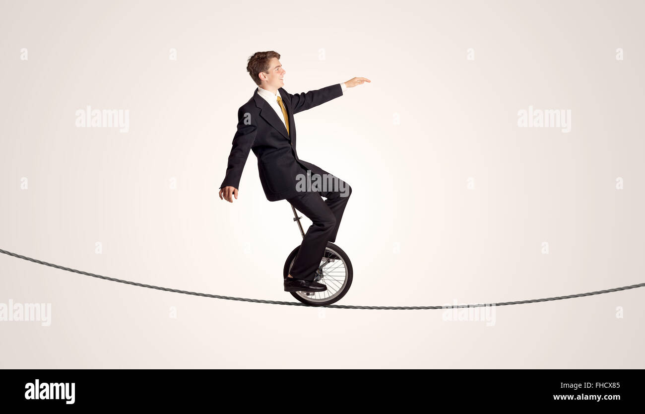 Extreme business man riding unicycle on a rope Stock Photo - Alamy