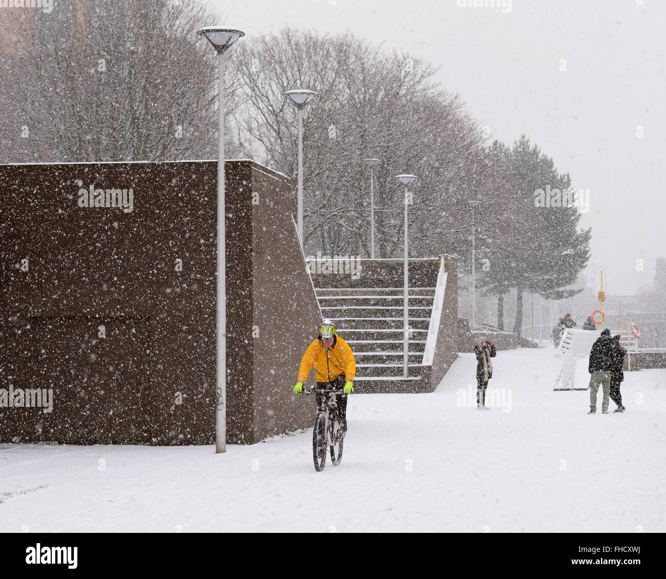 A cyclist braving a snowy day on Custom house quay walkway, Clyde Street, Glasgow, Scotland, UK Stock Photo
