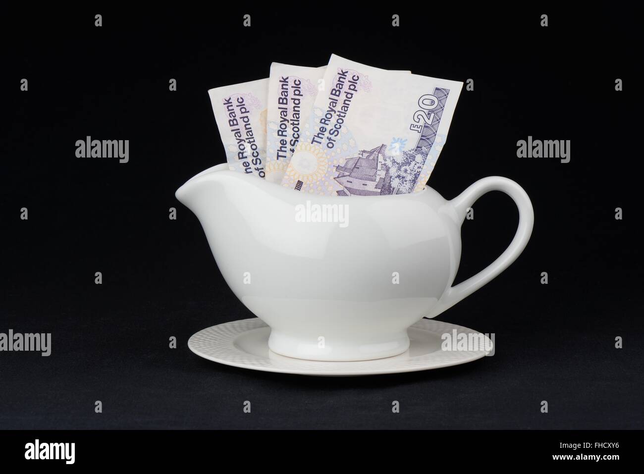 Concept image of 3 twenty pound notes of Royal Bank of Scotland denomination inside a gravy jug Stock Photo