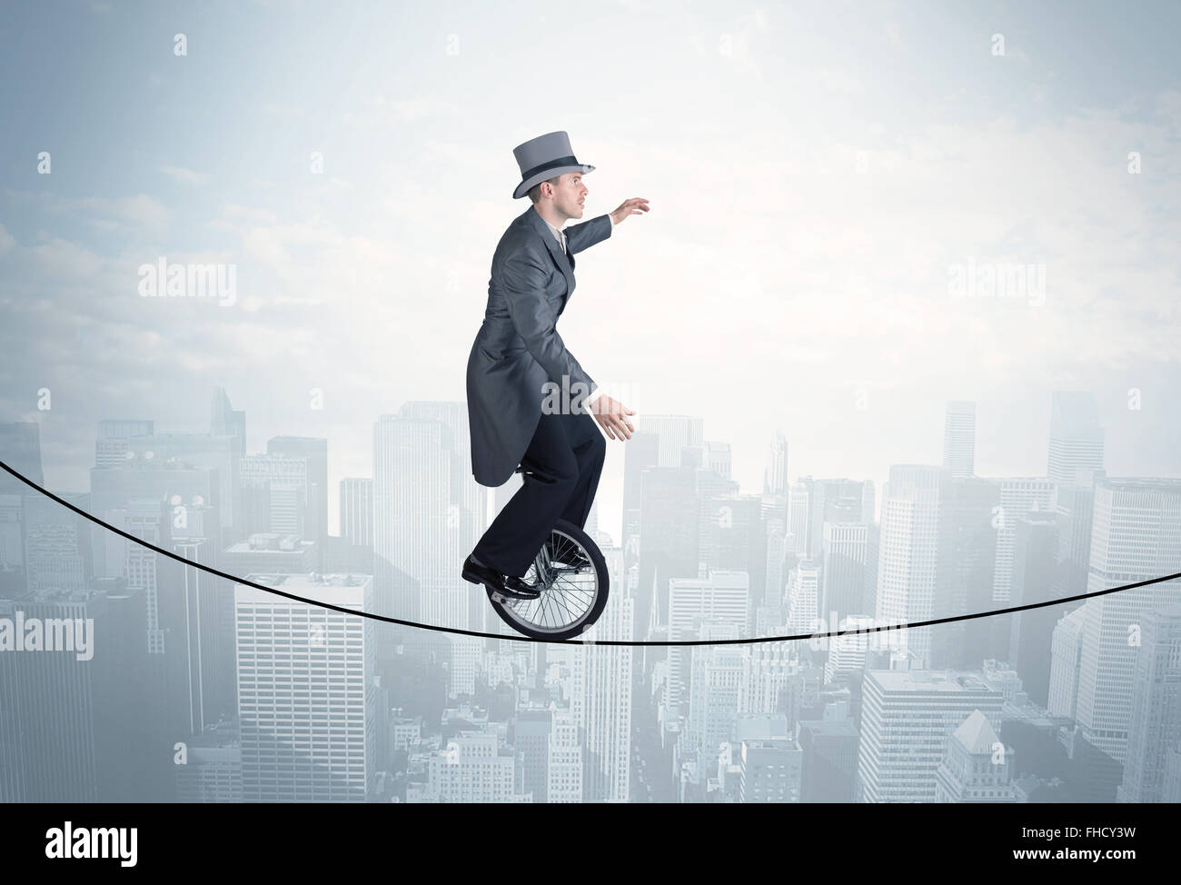 Brave guy riding a monocycle on a rope above cityscape Stock Photo