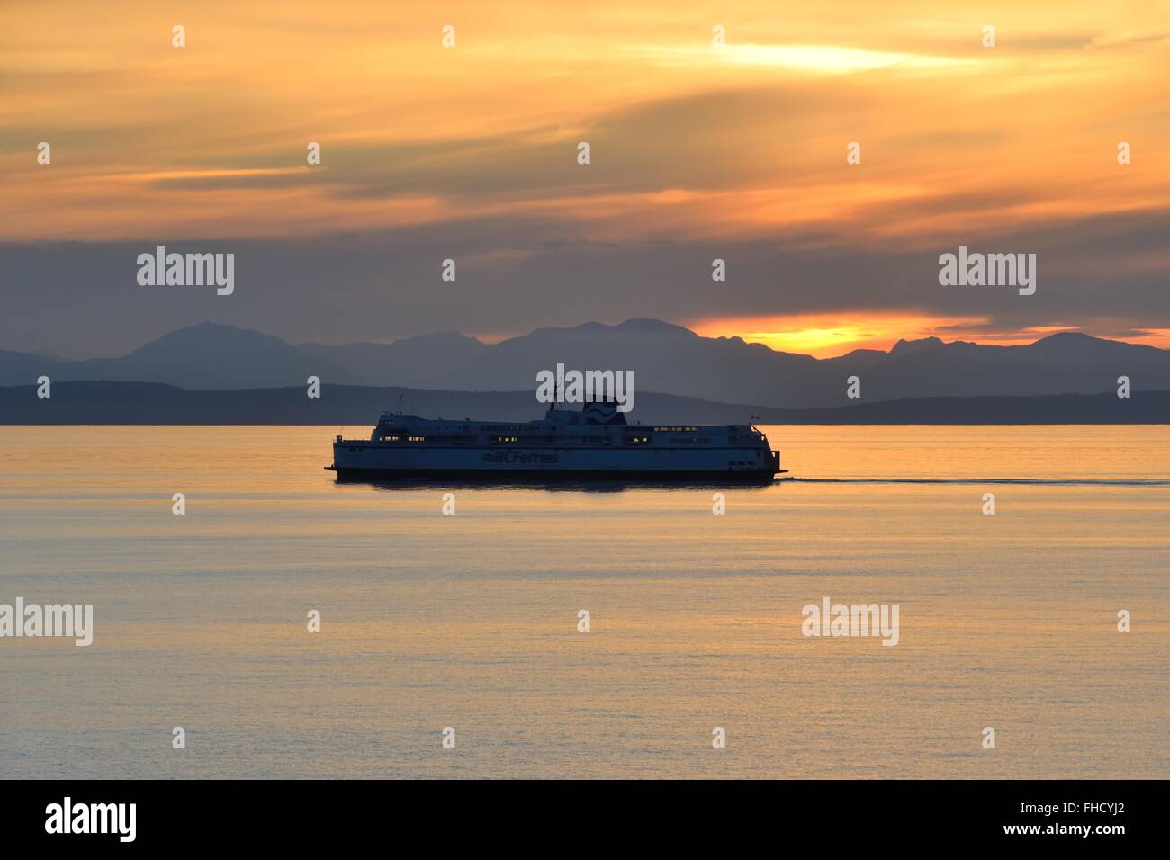 A BC ferries ferry sails though the channels of the North Pacific Ocean in Southern Alaska at sunset Stock Photo