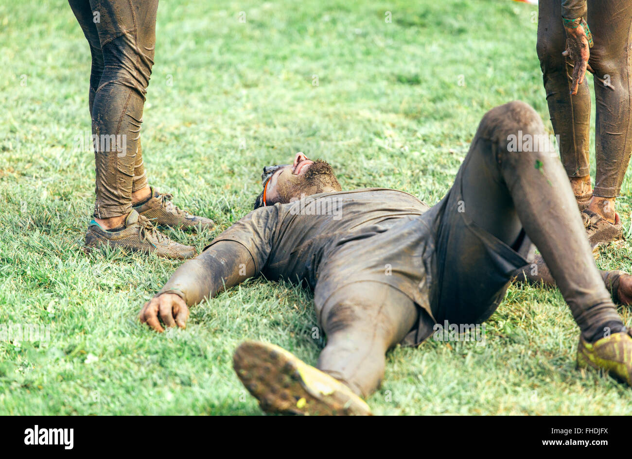 Participant in extreme obstacle race lying exhaustedly on grass Stock Photo