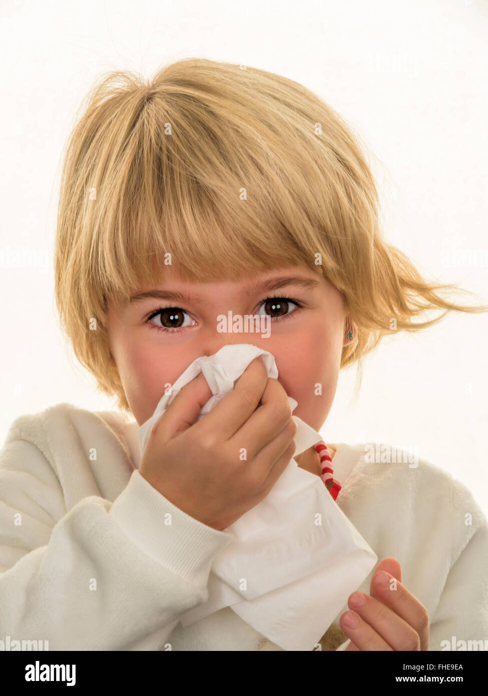 Portrait of blond girl blowing her nose Stock Photo