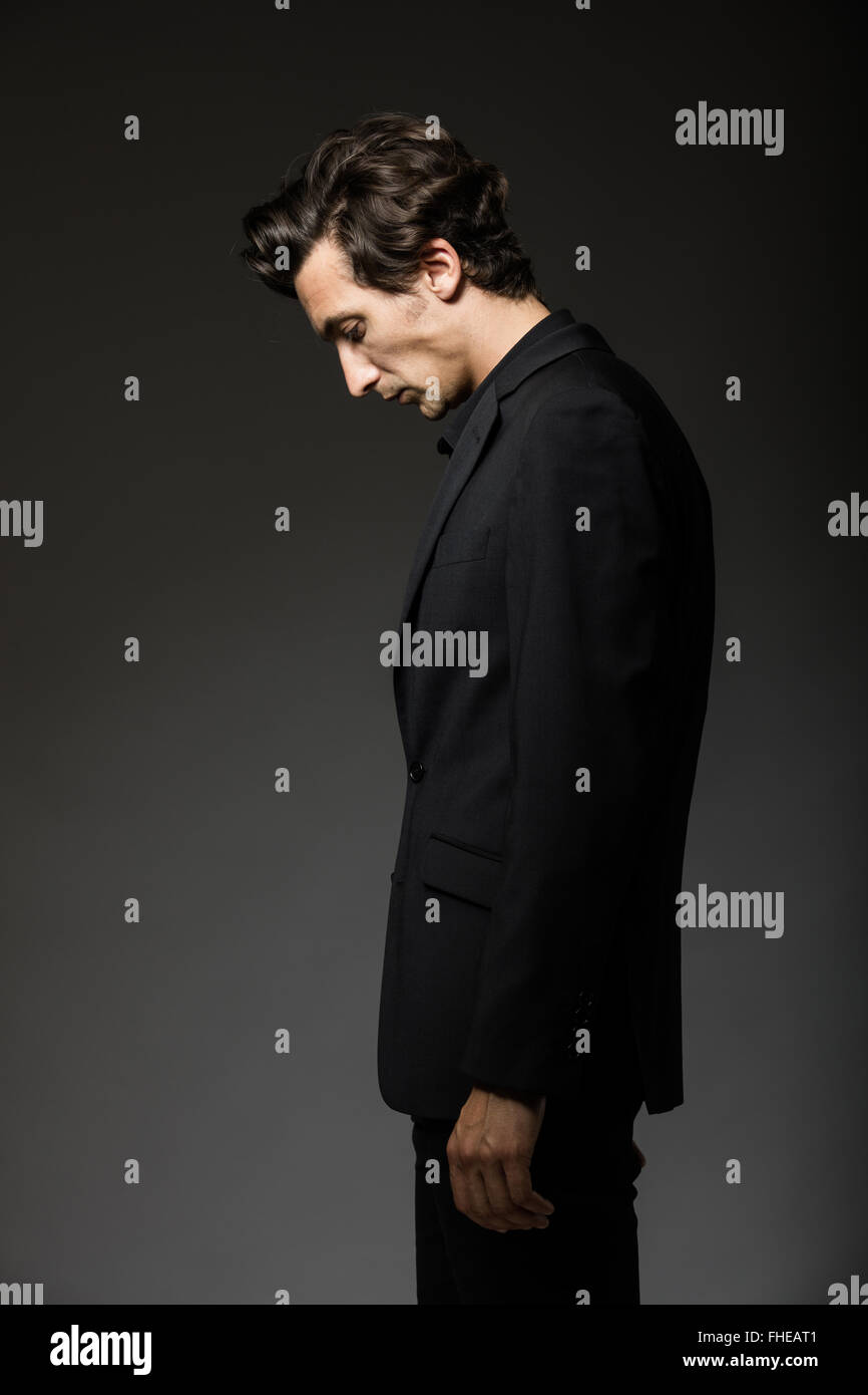 attractive man in black suit on dark background acting Stock Photo