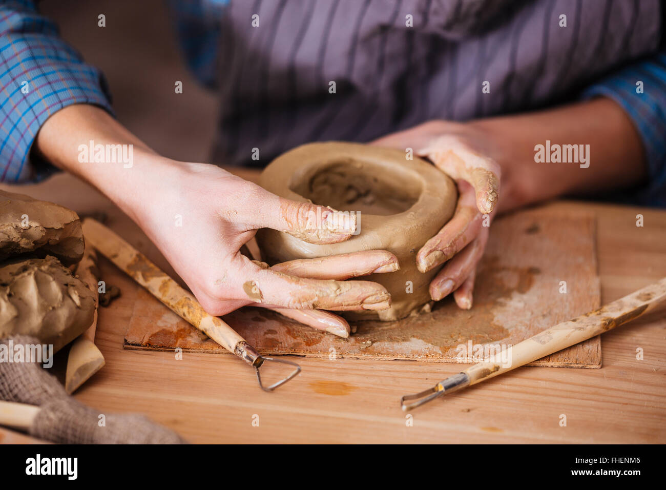 Closeup of clay pot making by hands of young woman in pottery