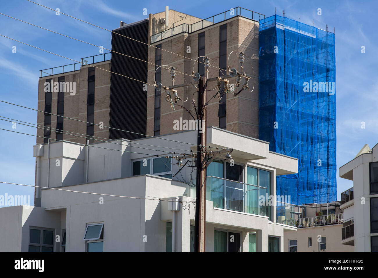 modern apartment building and backside of highrise building under construction, electric power pole in front Stock Photo