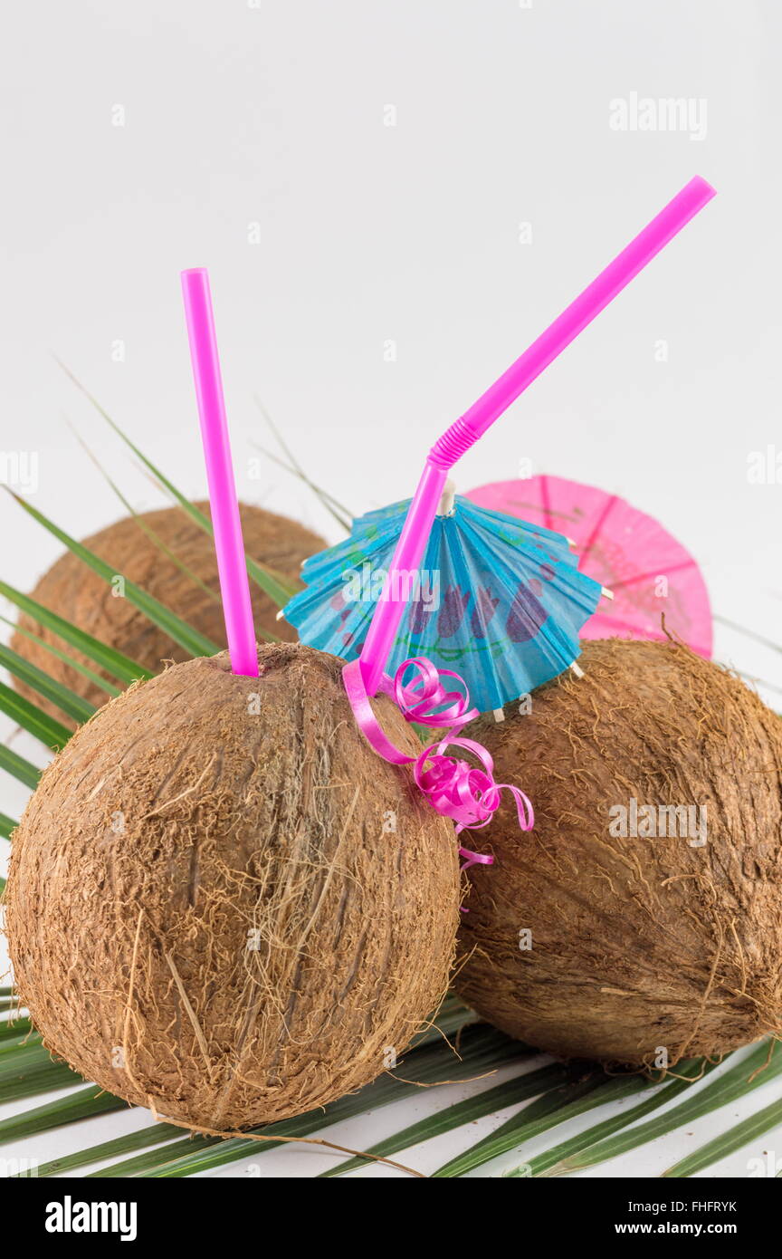 Fresh coconut cocktails with cocktail umbrella placed on coconut leaves Stock Photo