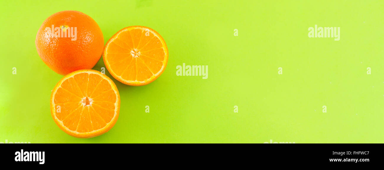 Whole and sliced oranges on green background Stock Photo