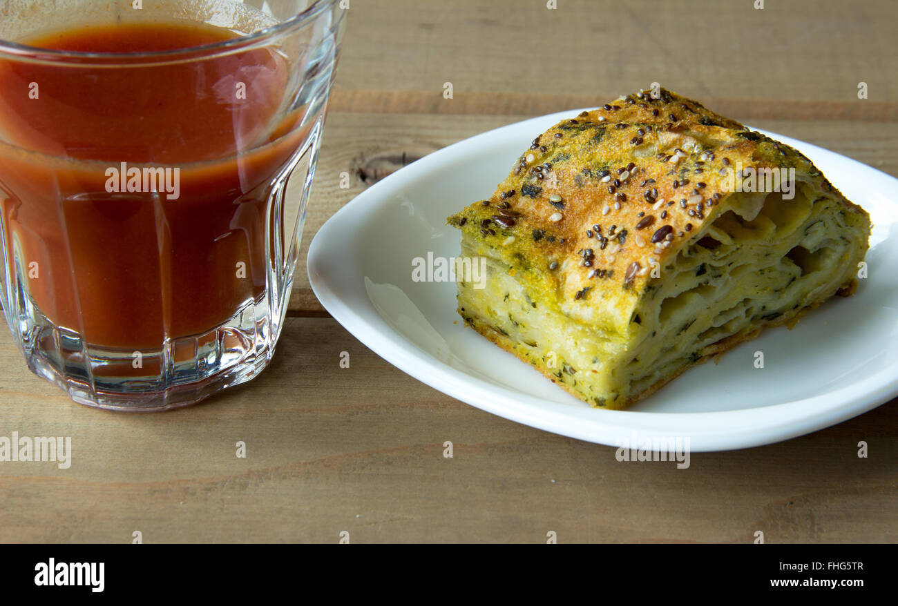 Spinach and cheese pie with a glass of tomato juice on a wooden table Stock Photo