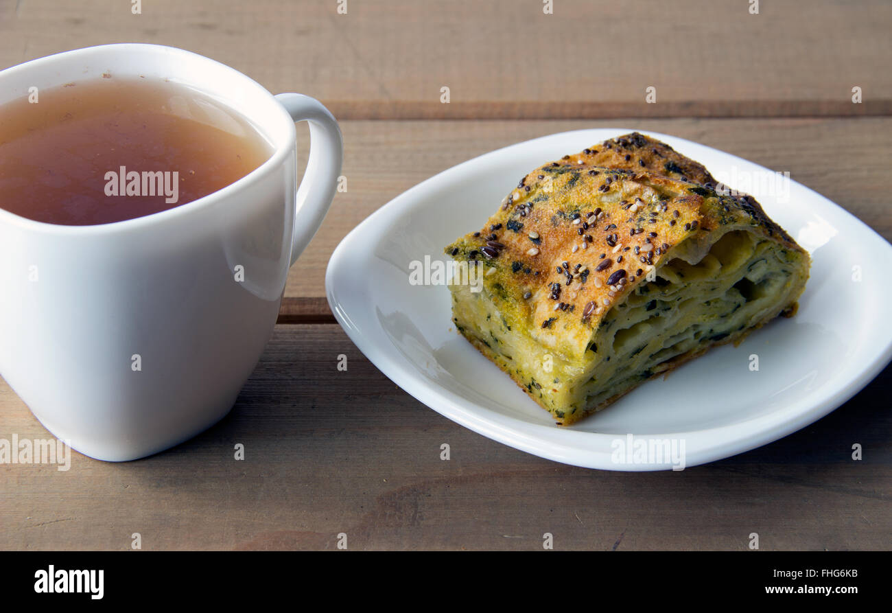 Spinach and cheese pie with a cup of tea on a wooden table Stock Photo