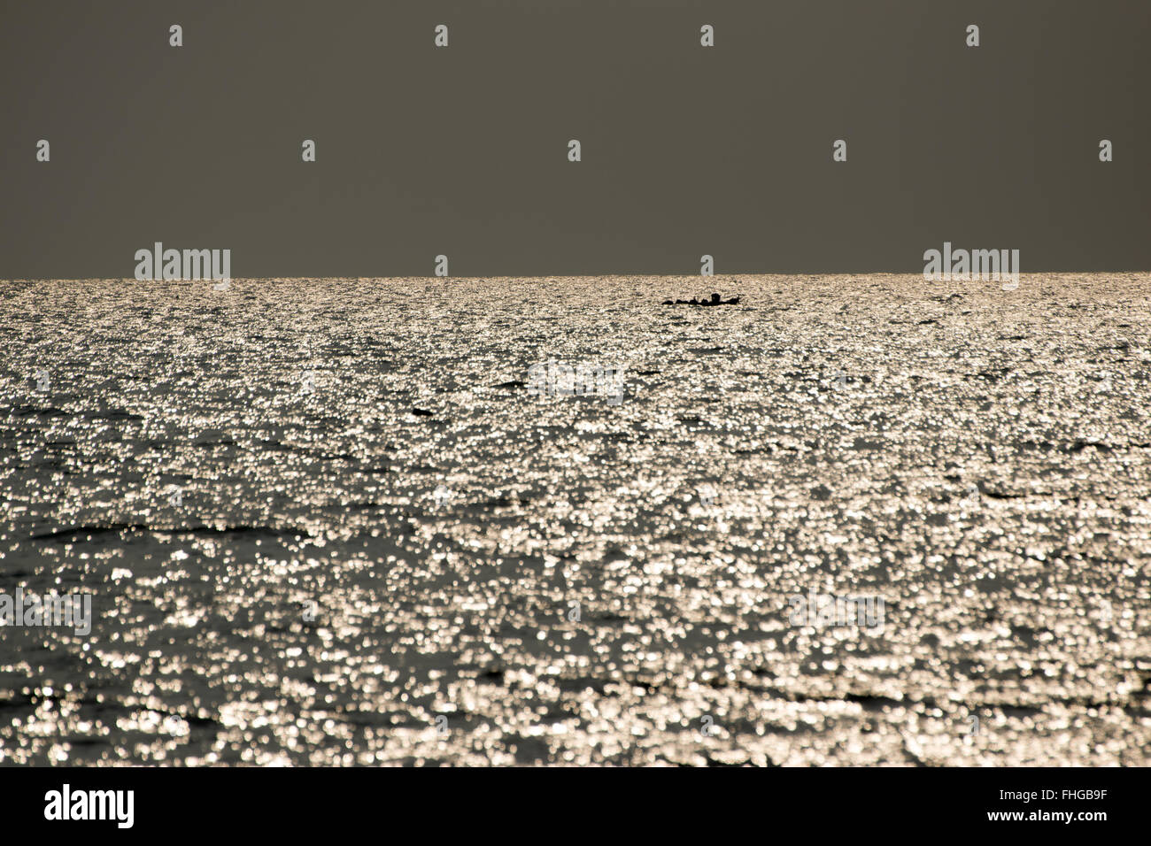 Fishing boat floating in the sea with the golden light of the morning sun. Stock Photo