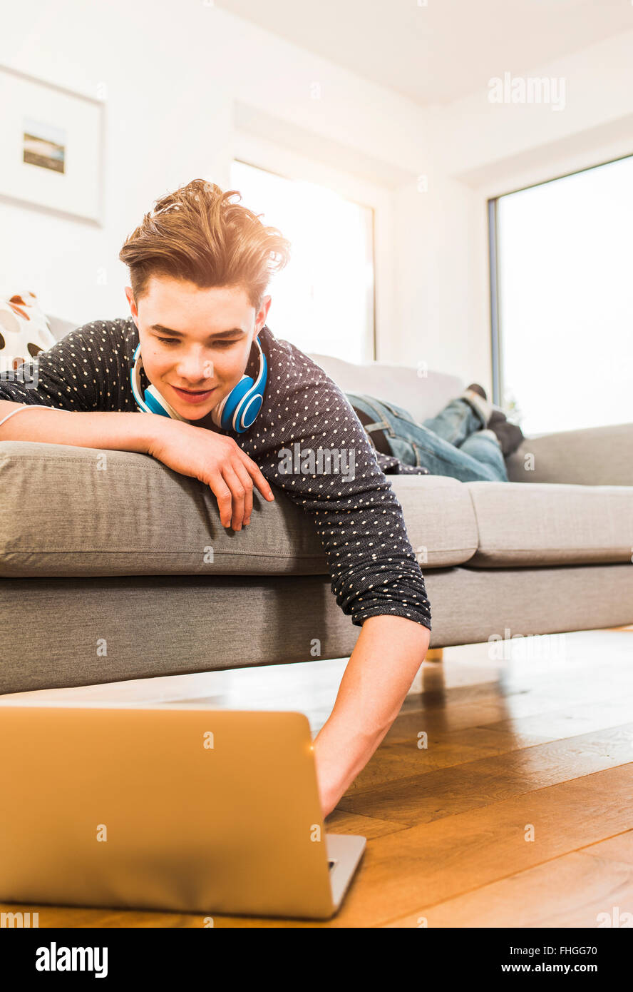 Young man lying on couch using laptop Stock Photo