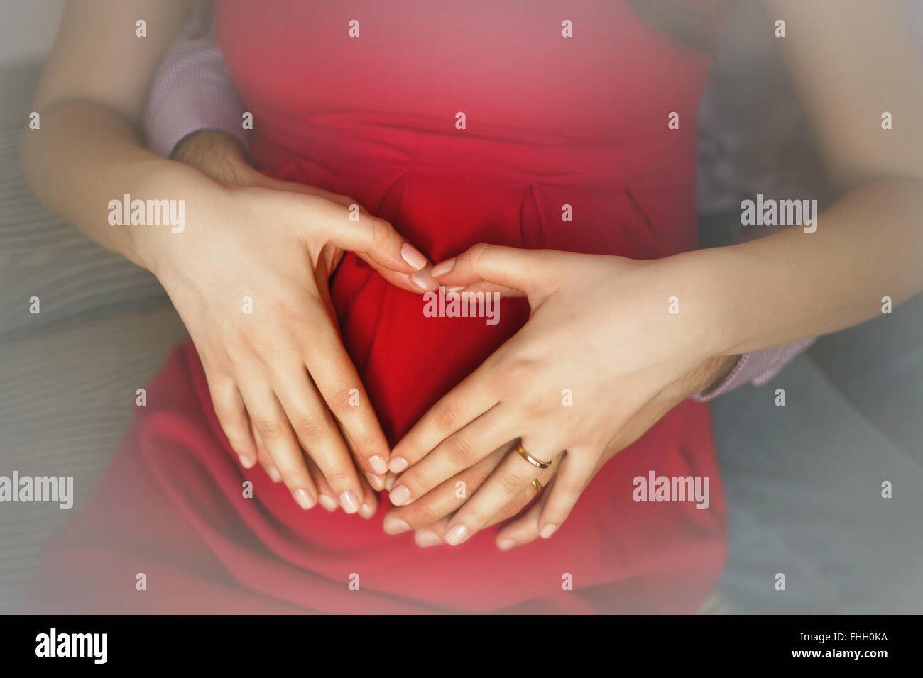 Pregnancy concept – love symbol by married couple hands Stock Photo