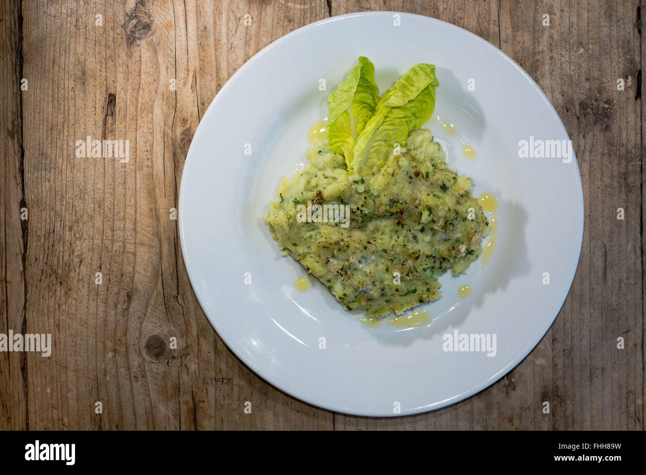 Fish pie from above. Fish pie with potato and herbs served with olive oil and lettuce Stock Photo