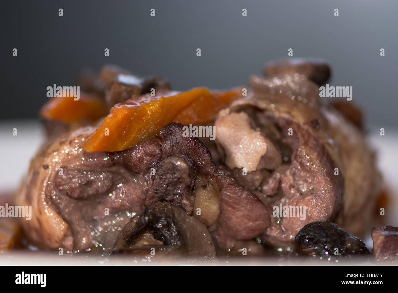 Coq au vin detail from side. Classic French chicken dish prepared served with vegetables in red wine Stock Photo