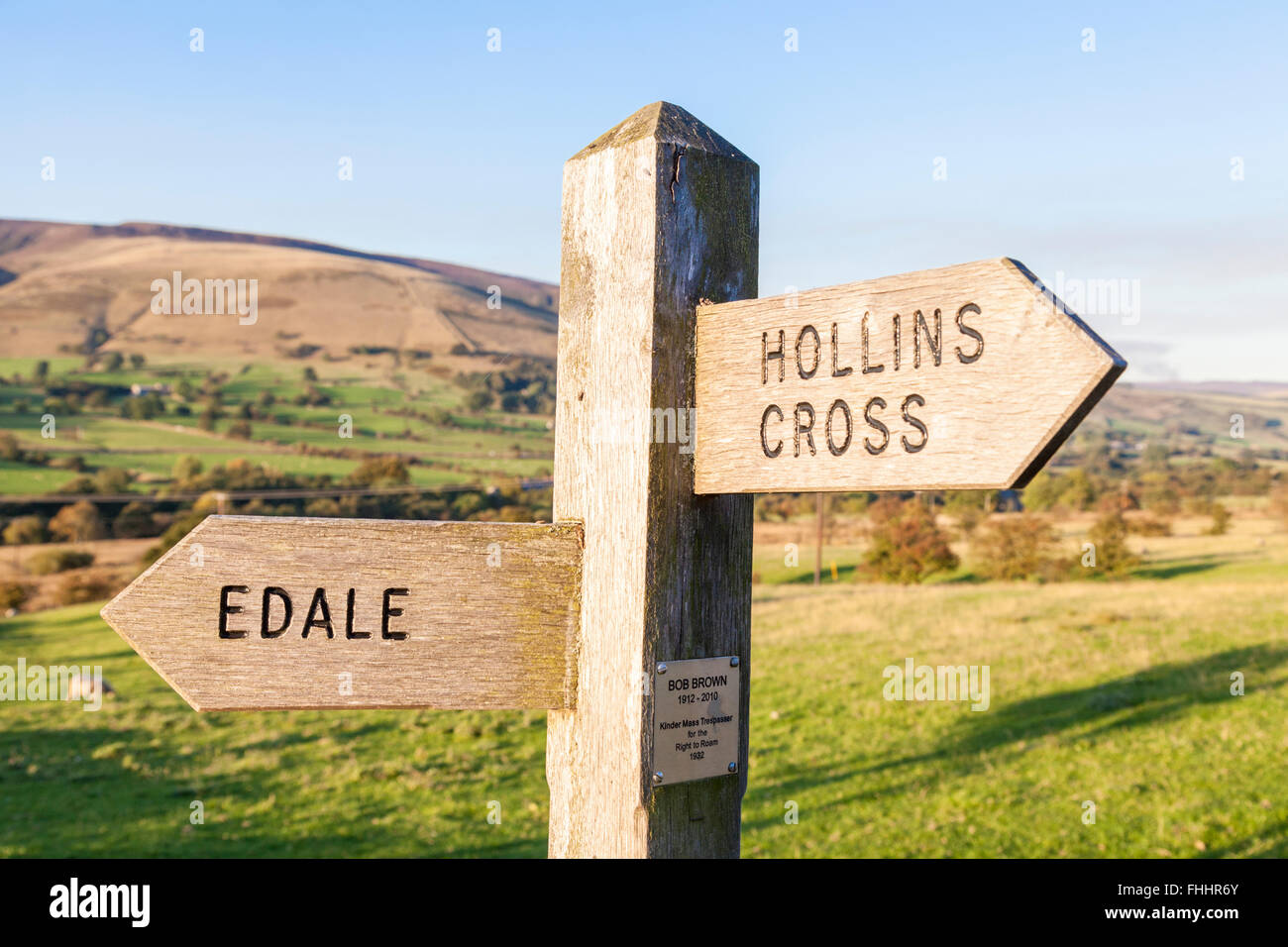 Wooden footpath sign post for Edale and Hollins Cross with memorial plaque to Bob Brown, Kinder Scout mass trespasser, Derbyshire, England, UK Stock Photo