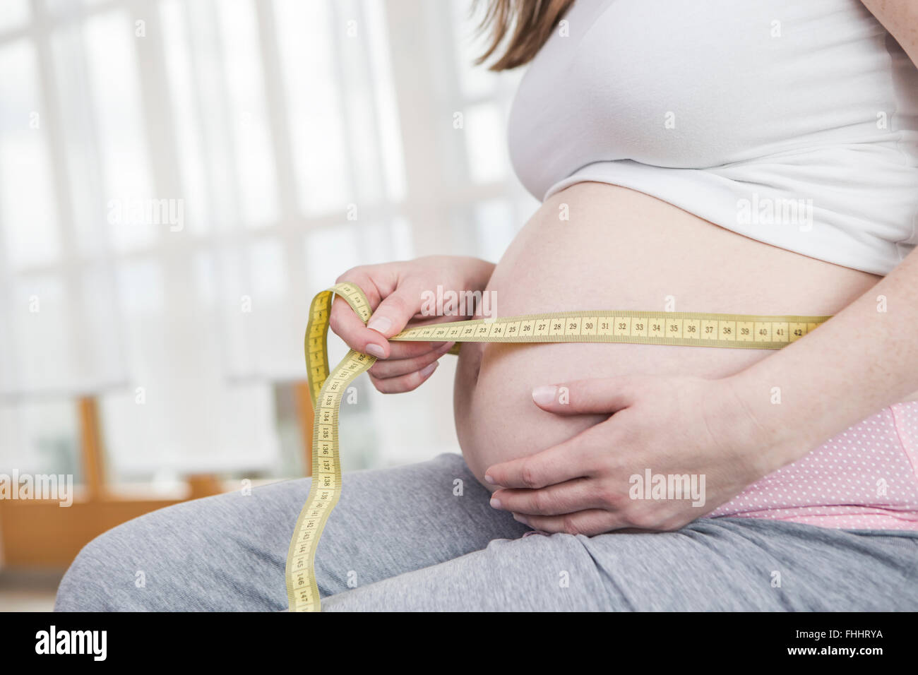 Pregnant woman measuring her belly circumference Stock Photo